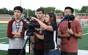  TV and Film teacher with students filming football game
